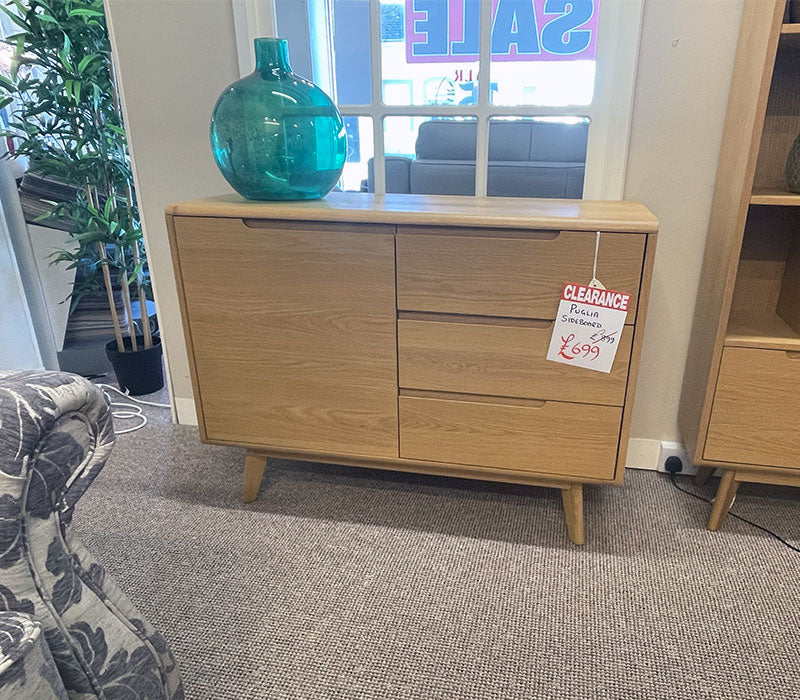 Wooden sideboard with a blue vase on top in a furniture showroom.