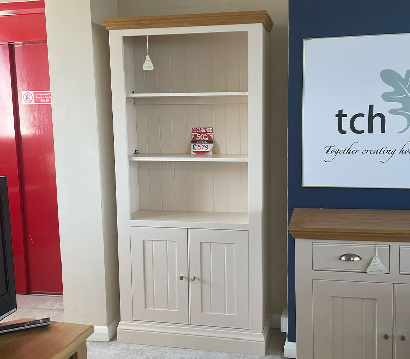White bookshelf with wooden top and base, next to a blue wall .