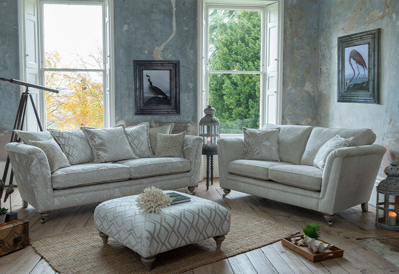 Living room with two beige sofas, an ottoman, and decorative items.