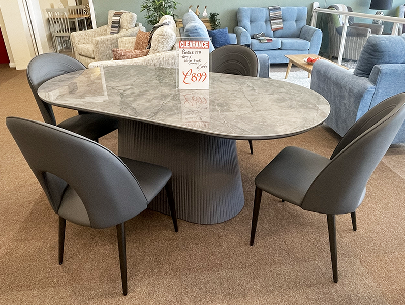 Oval dining table with a ceramic top with chairs in a furniture showroom 