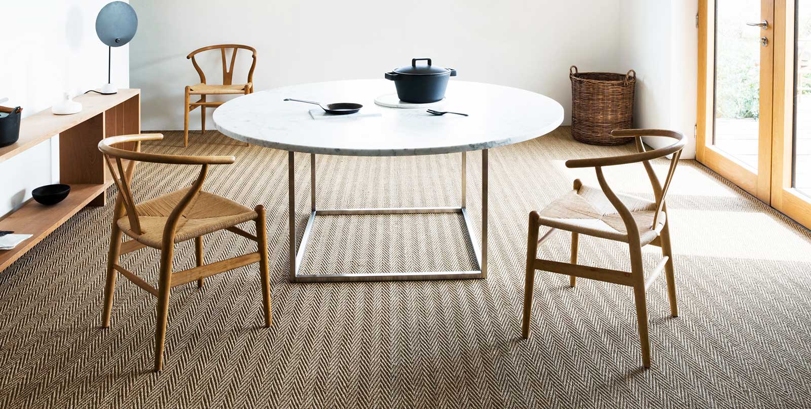 A seagrass floor covering/carpet in a room with a circular table and 3 chairs.