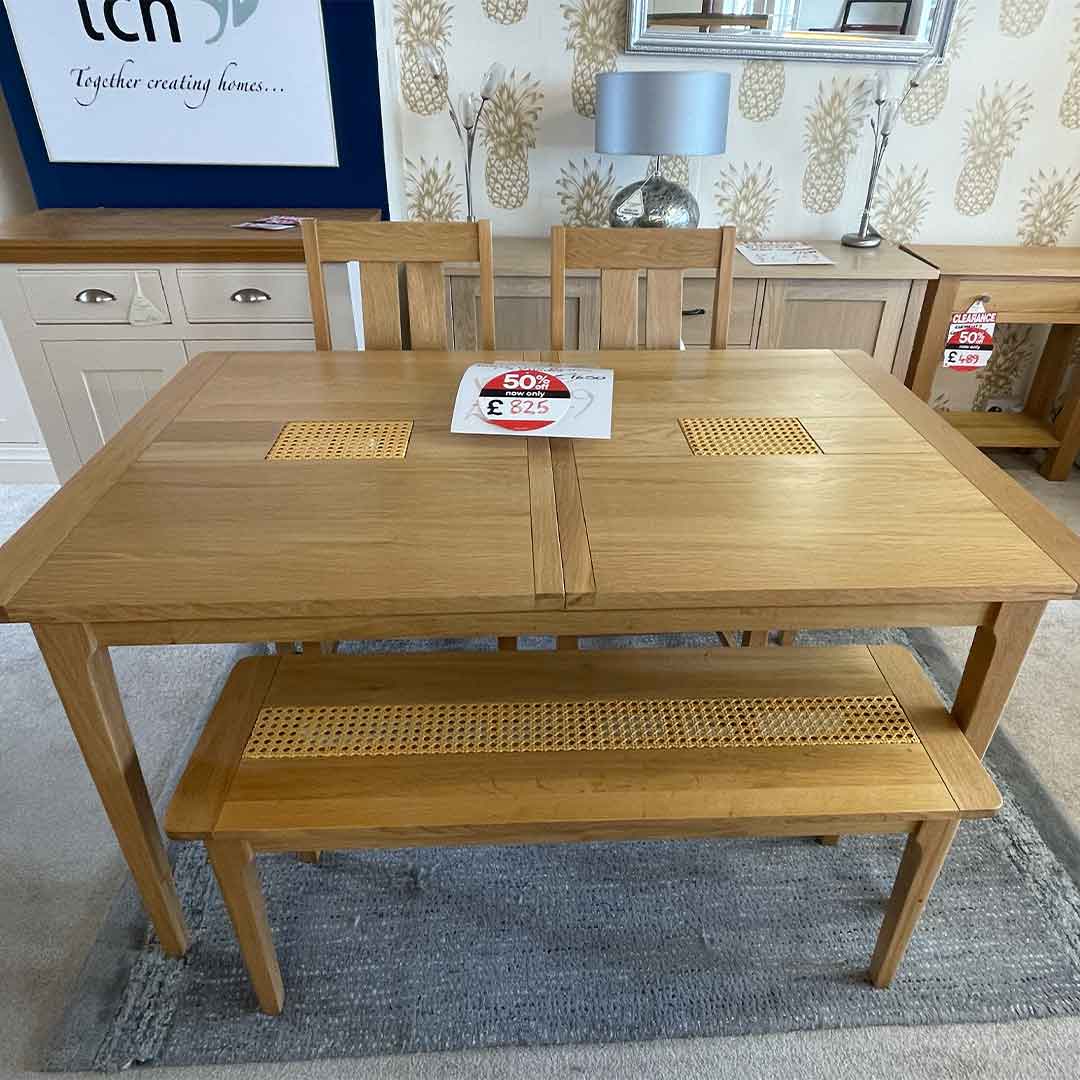 Dining table, two chairs and a bench with in a light oak with a wicker panel in the table and bench.