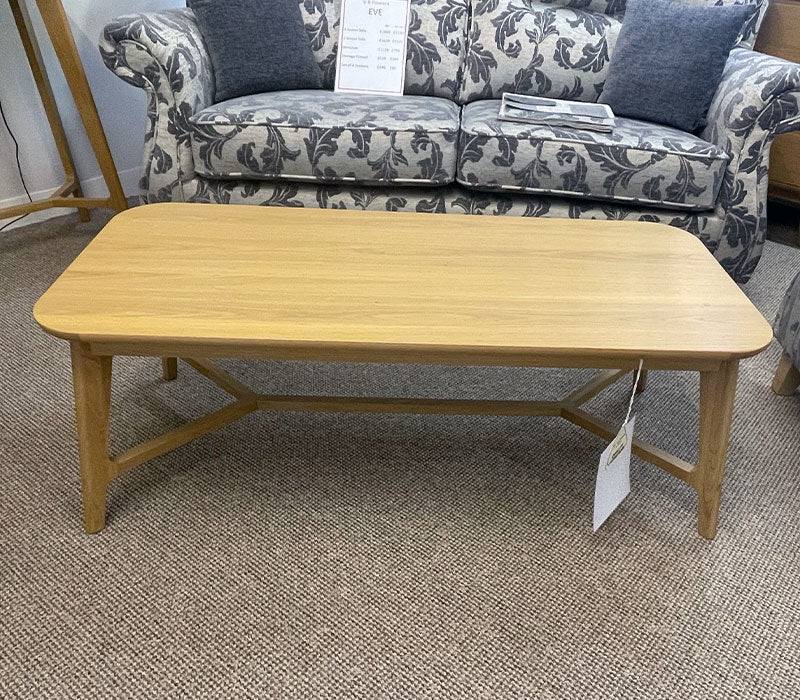 Wooden coffee table with a floral-patterned sofa in the background