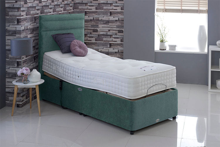 Green bed frame with white mattress in a room with a stone wall and window.